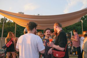 three people at an outdoor drinks event in the sunshine