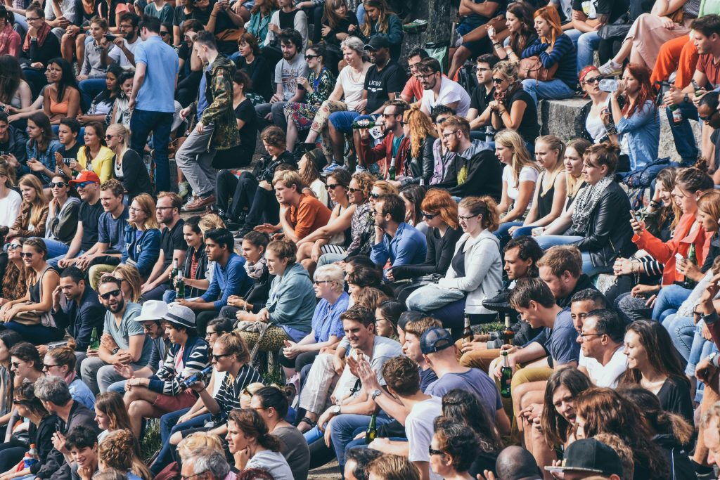 Large crowd on tiered seating drinking in the sun