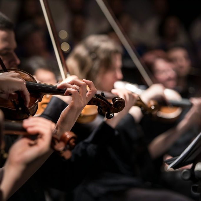 Violins playing in a group on stage